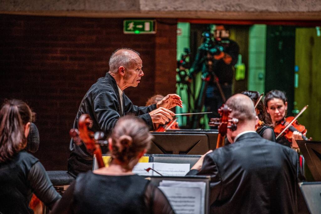 A conductor conducts in the centre of an orchestra